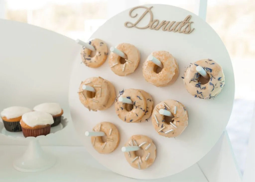 Donuts with blue, white, and brown sprinkles on a round donut stand.