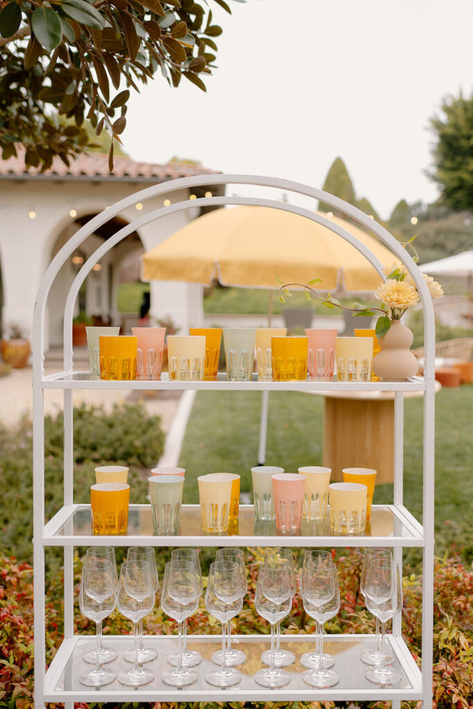 Cups on a curved white shelf outside for a party.