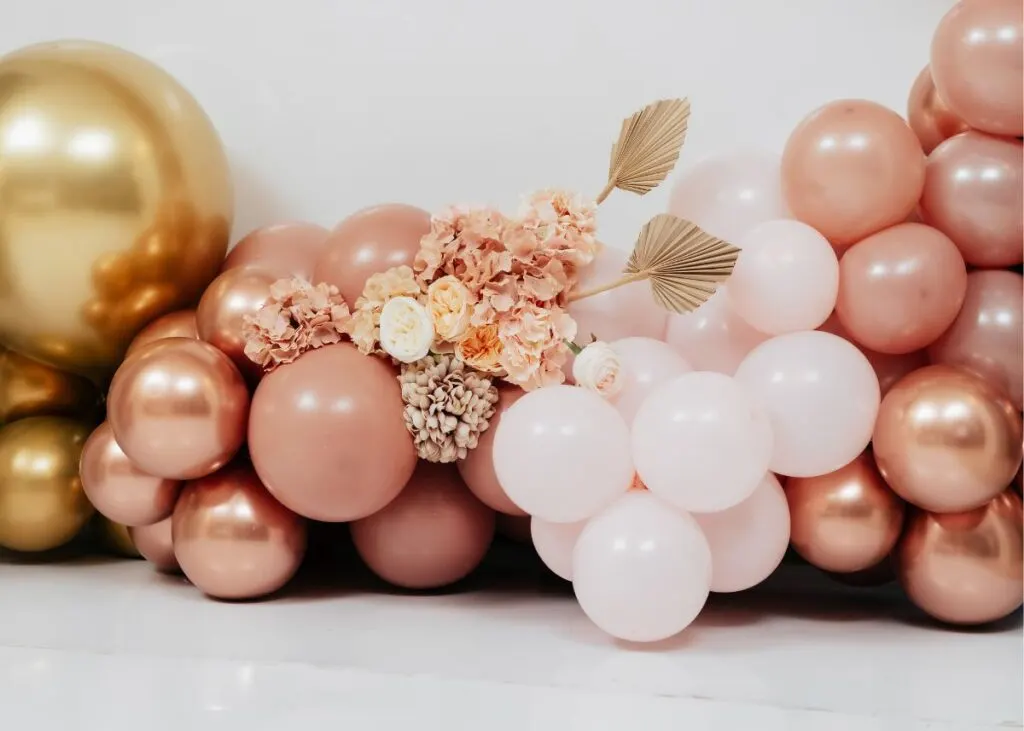 Dusty pink, light ink, and gold balloons with a floral arrangement.
