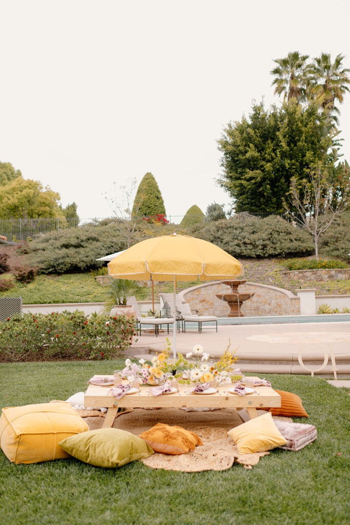 A table and pillows outside for a baby shower in yellow and orange.
