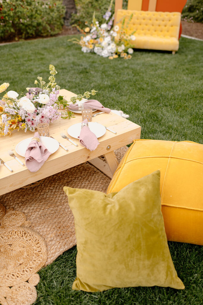 A table and pillows on a lawn setup for a baby shower.