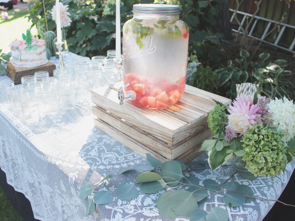 A dispenser filled with water and fruit on a baby shower food table.