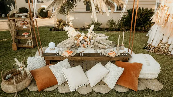 A low table sits outside with white and brown pillows and boho table decor.