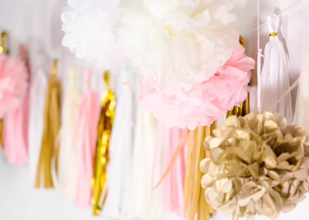 Pink, white, and gold tassel garland and tissue paper puffs.