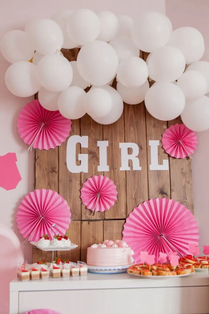 Pink and white girl baby shower food table with balloons.