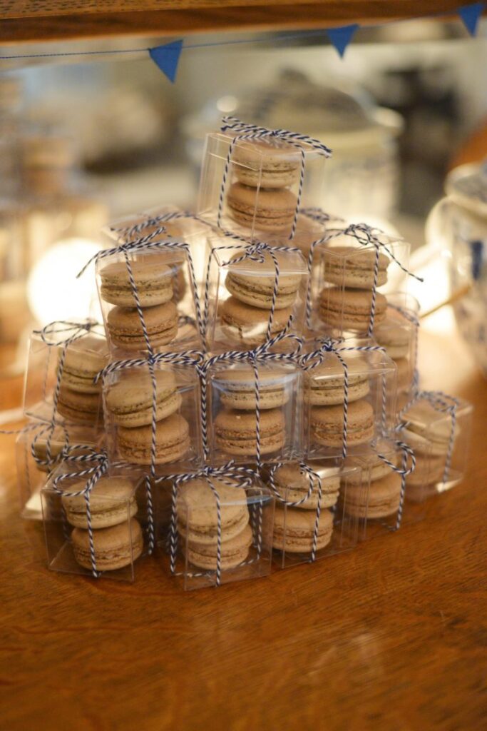 Cookies in clear boxes with blue and white striped twine tied around them stacked on a table.