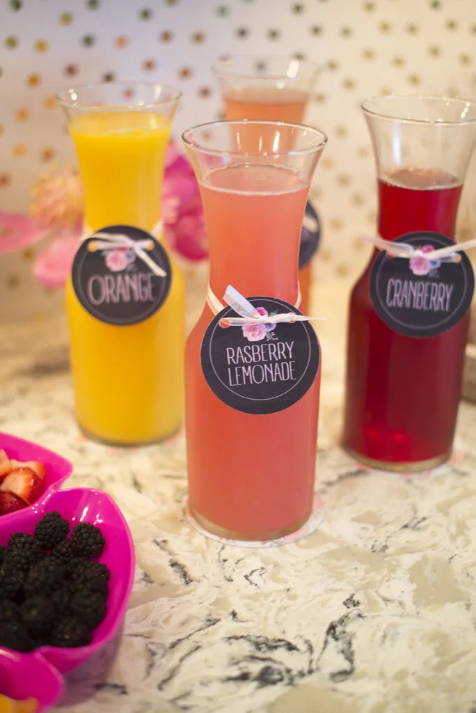 Mini pitchers of juice on a counter next to party food.