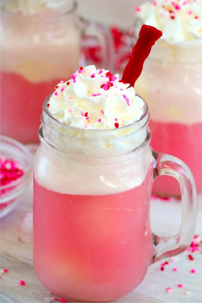 Cherry float in a mason glass jar with whipped cream and a licorice rope.
