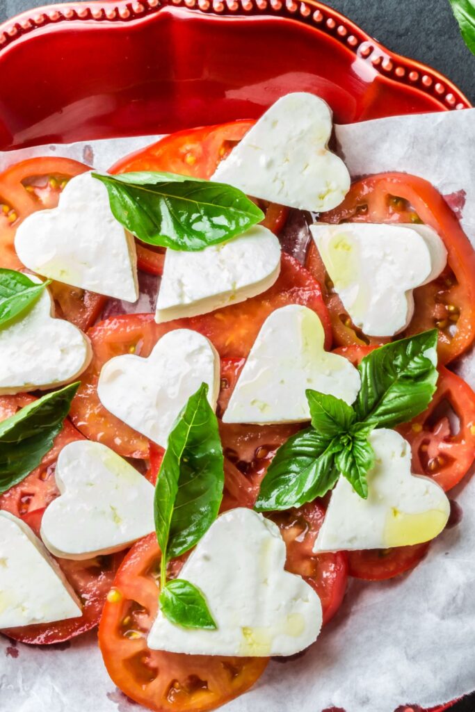 Caprese salad with tomatoes, basil, and heart-shaped mozzarella cheese slices.