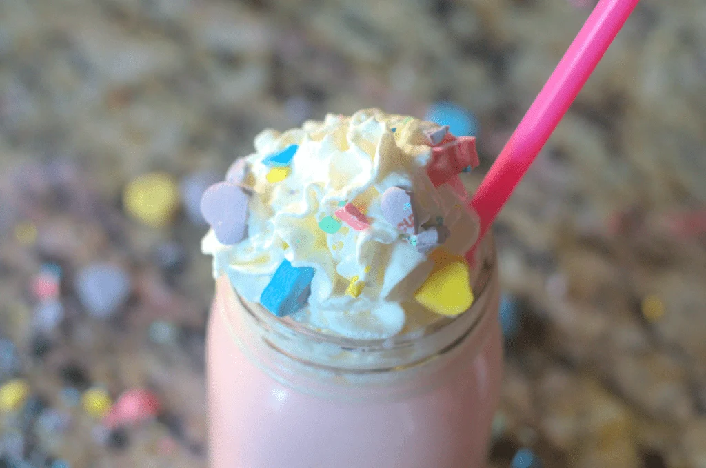 Valentine's day conversation hearts drink with whipped cream and candies on top.
