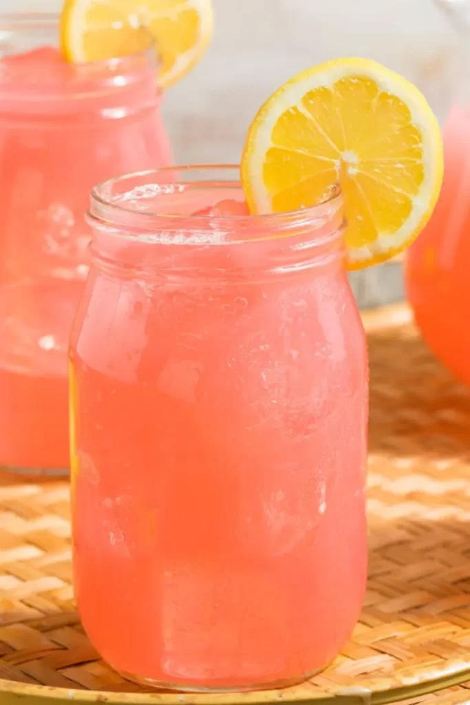 Mason glass jars with pink lemonade and lemon slice garnish.