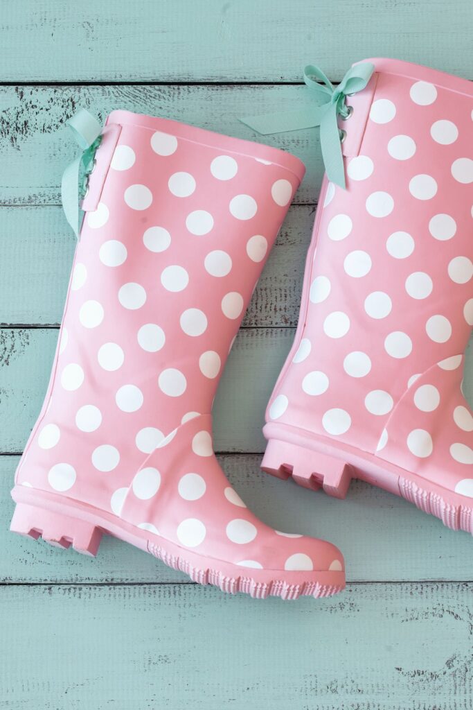 Pink and white polka dot rain boots with a teal tassel.