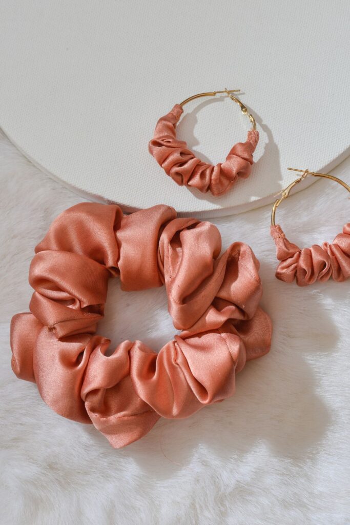 A dusty pink silk hair scrunchy with a set of matching earrings.