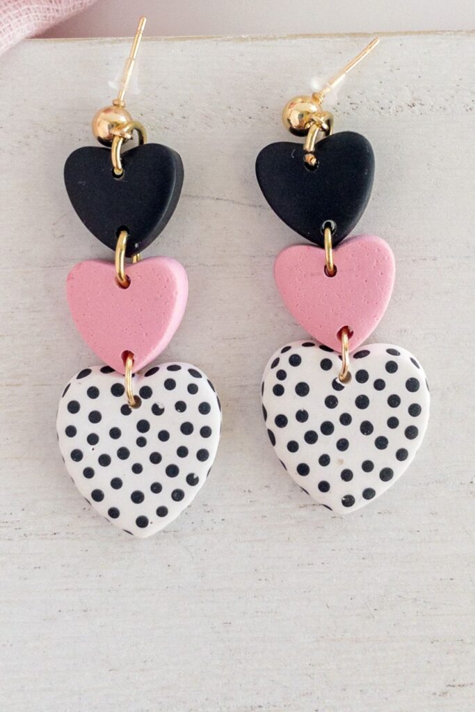 Three-tiered heart earrings with a black heart, pink, heart, and white and black polka dot heart.