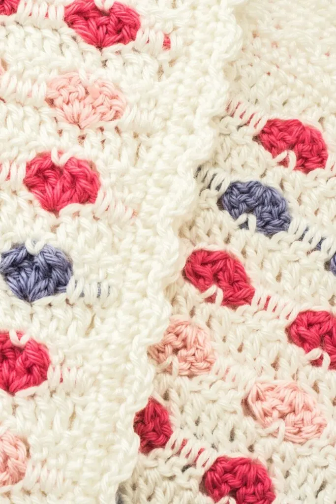A knit blanket with blue, red, and pink hearts in the pattern.