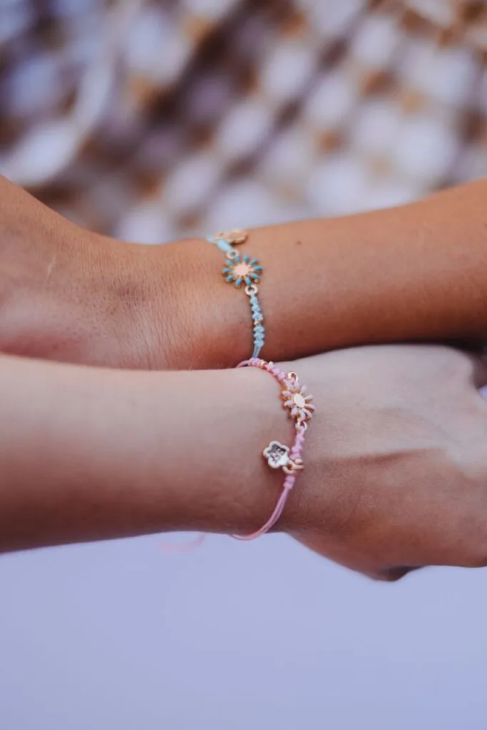 Two arms close together with matching bracelets around each wrist.