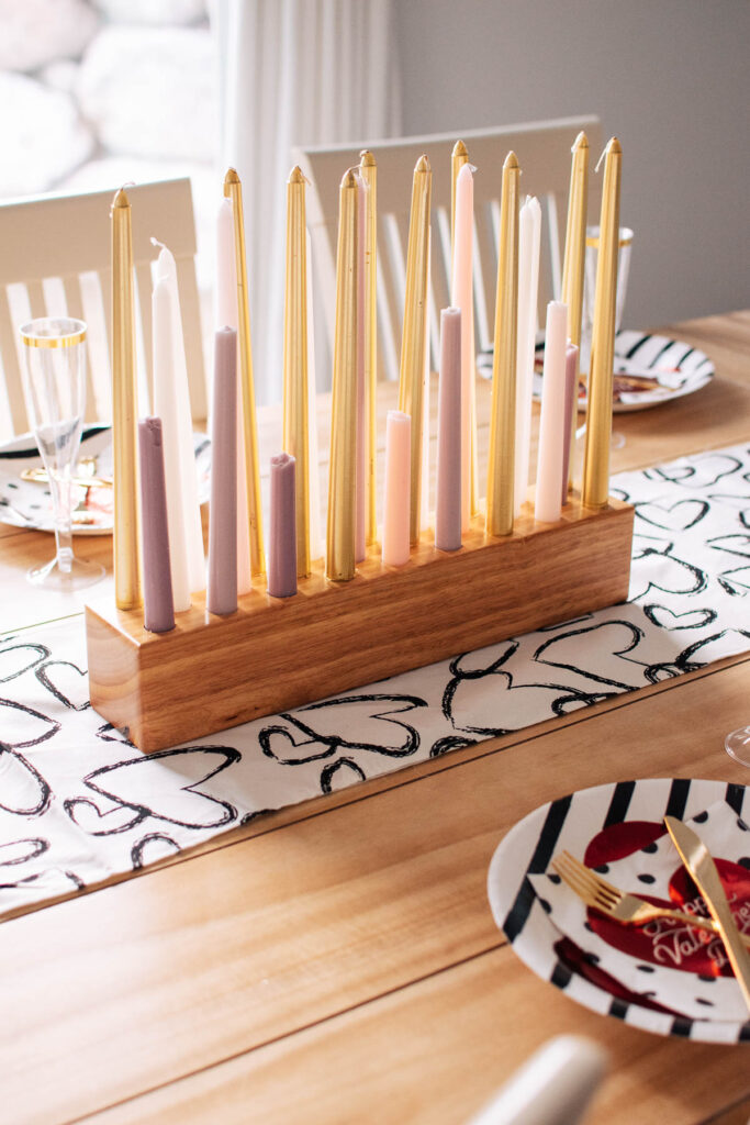 Wood candle holder with several pink, purple, gold, and white candles.