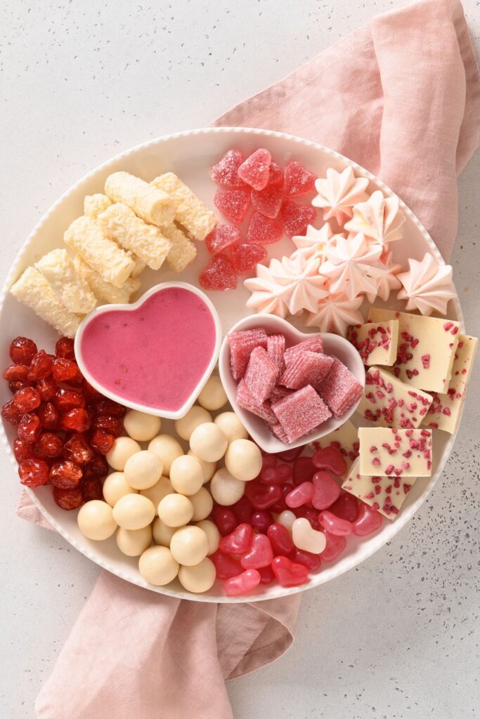 Grazing platter with heart-shaped dishes, candies, and sweets.