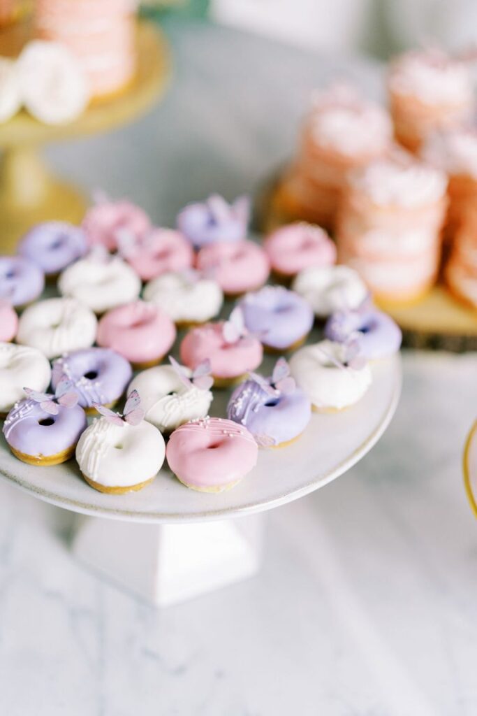 Pink, purple, and white mini donuts with butterflies on top.
